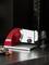 Electric all-purpose slicer with a red casing on a kitchen worktop. Sliced cold meats and a glass of red wine are positioned beside it.