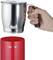 A hand is holding a silver milk frother jug over a red container. The red container is labelled 'GRAEF'.