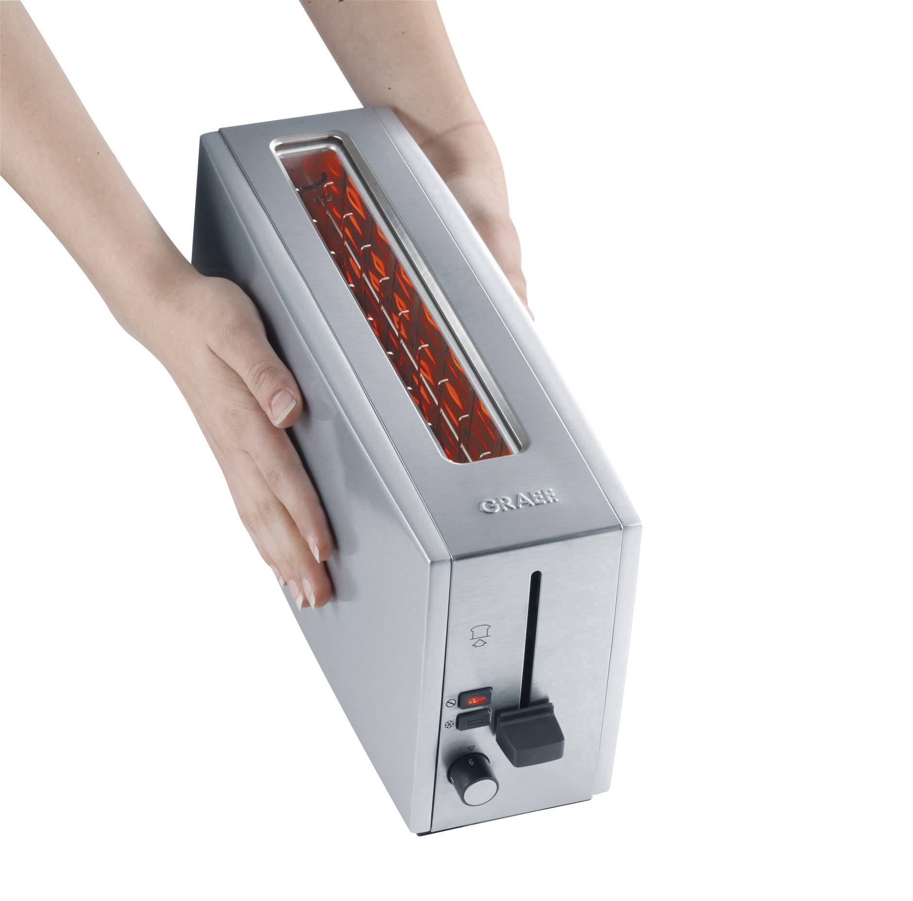 A person is holding a silver toaster, with bread slot and heating elements visible. The toaster has a lever and an indicator light.