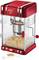 Red and white popcorn machine with popcorn inside. Small scoop with unpopped corn kernels beside it.