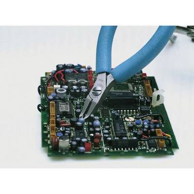 A pair of pliers cuts a wire on a circuit board. The PCB is populated with various electronic components.