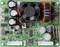 A green printed circuit board with multiple capacitors, inductors, connectors and a small fan, representing electronic components.