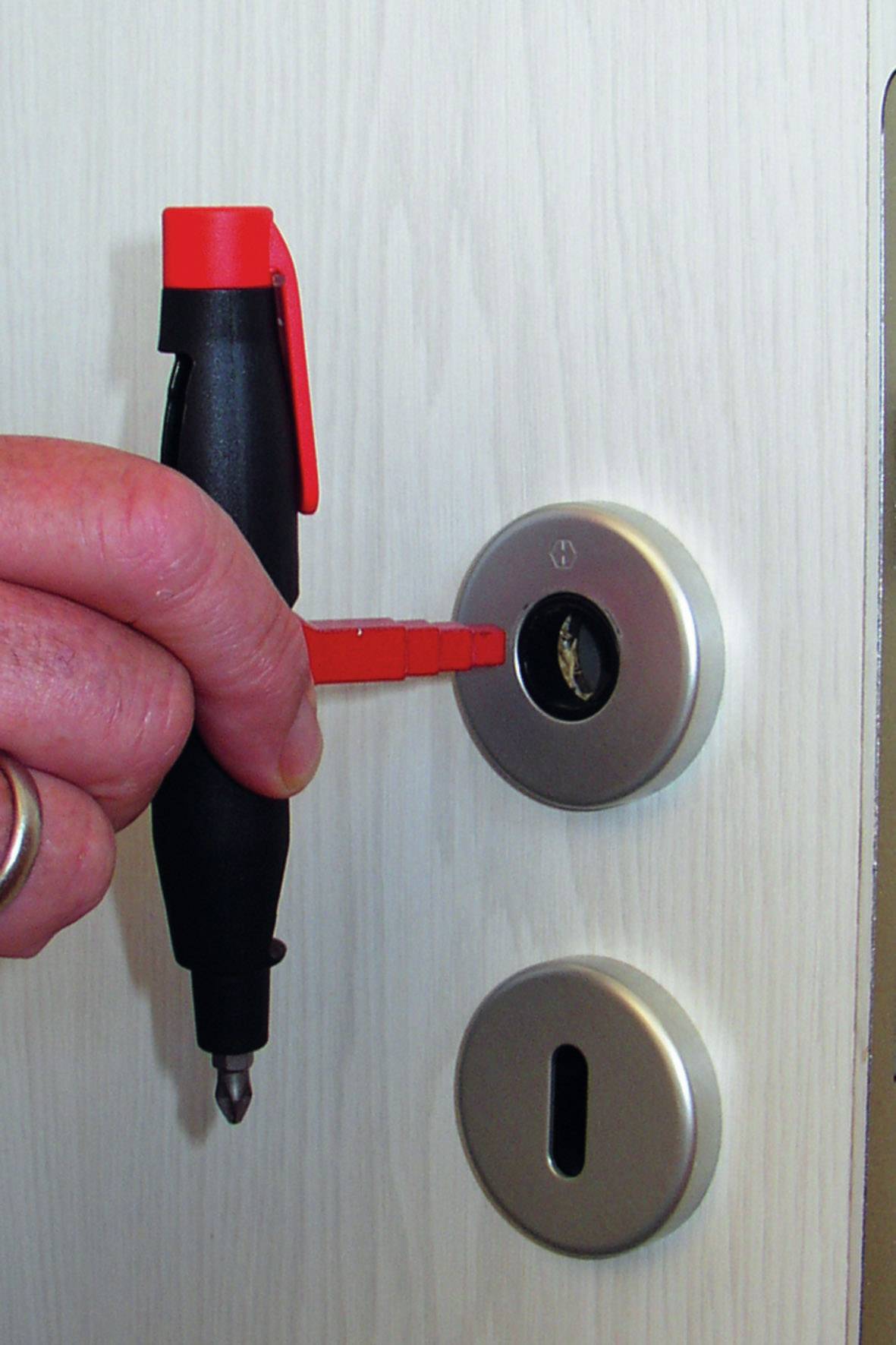 A hand is holding a de-icing spray for a door lock in front of a lock. The spray has a red cap and a dispenser.