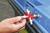 A hand holds a red universal key and opens a locking mechanism on a blue skip.