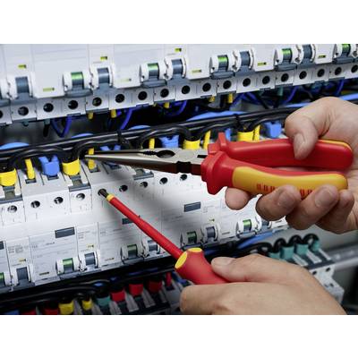 'Close-up of a person working on a fuse box with pliers and a screwdriver to maintain or disconnect electrical connections.'
