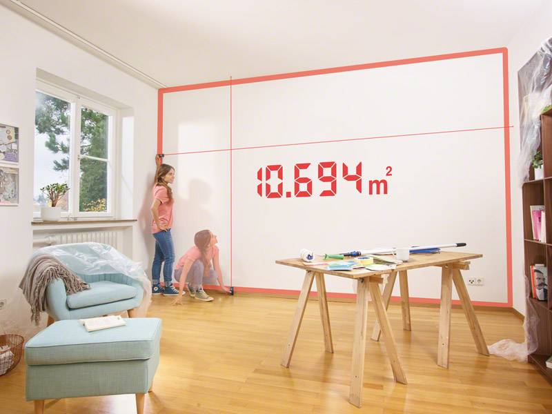 A girl in a living room is looking at a red digital display on the wall showing '10,694 m²', possibly for room measurement purposes.