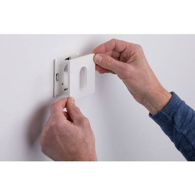 Two hands are fitting a white cover plate onto a wall socket.
