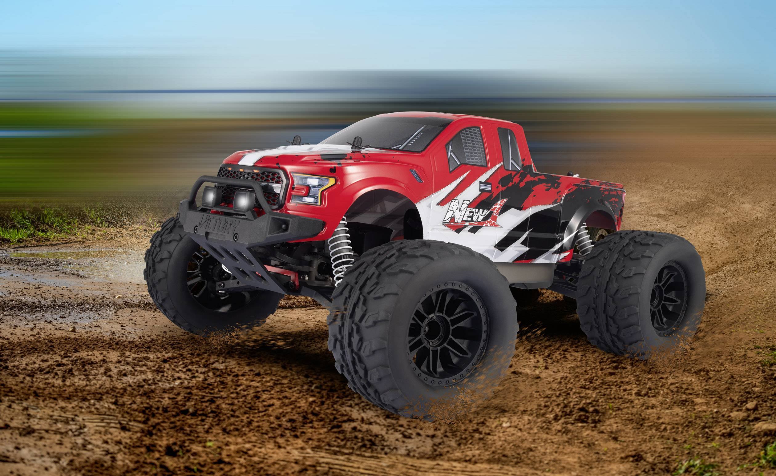 A red RC monster truck is speeding along a muddy track. It has large, robust tyres and a sporty appearance.