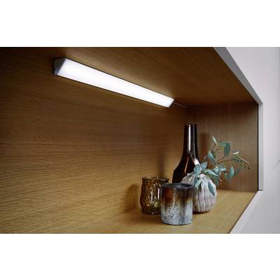 A lit shelf with a vase, a small plant branch and two differently shaped candleholders.