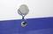 Blue fabric with an eyelet attached to a round, silver hook on the wall.