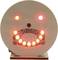 Wooden disc with illuminating red and yellow LEDs forming a smiling face.