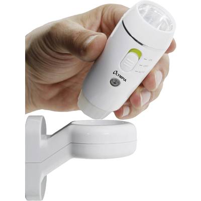 A hand holds a white, portable lamp with a switch and logo. The lamp is supported by a wall mount.