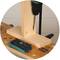 'A drill is working on a piece of wood on a table with a measuring scale, with an angle gauge lying on it.'