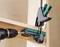 A drill with a wood drill bit is drilling through two wooden boards secured with a green G-clamp.