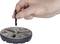 A human hand is holding a small key over a circular metal device, likely for tightening or loosening parts.