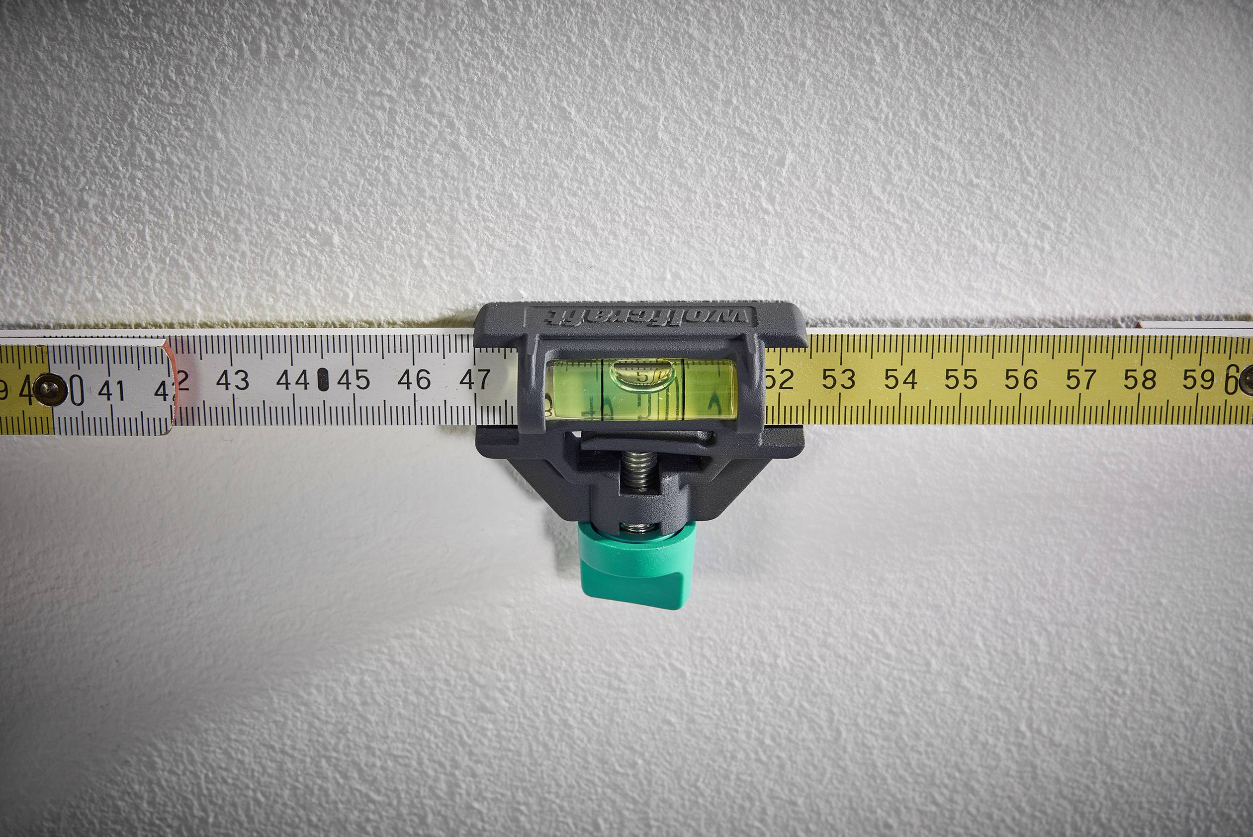 'Spirit level with tape measure against a wall showing horizontal alignment.'