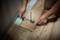 'A person is measuring the floor covering with a measuring tool to adapt planks to the wall.'
