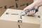 A hand is using a craft knife to cut adhesive tape from a cardboard box with a 'wolfcraft' logo.