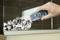 A hand holds an electric scraping tool and removes paint from a glass surface. The background shows tiles.