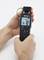 A hand is holding a digital measuring device displaying '74' and '10%'. It is evidently being used to measure humidity.