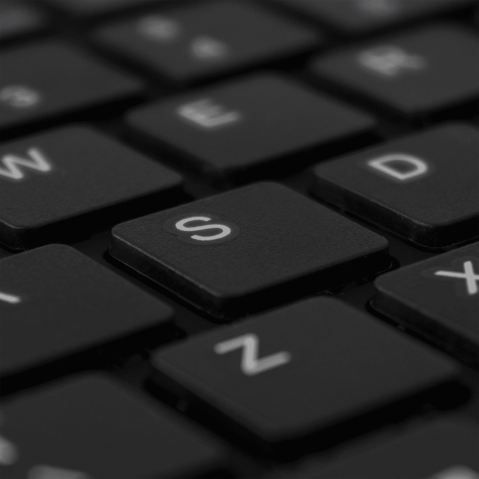 Close-up of a computer keyboard, with the focus on a black 'S' key.