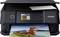 A black printer is printing a colourful photo of a boat on a lake with hills in the background, representative of photo printing.
