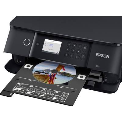 A printer is printing a photo of a beach onto a CD. The control panel shows that the printing process is in progress.