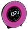 Round digital alarm clock with display showing '13:24', 'Monday', '31.12'. Surrounded by pink light. Brand 'TFA'.
