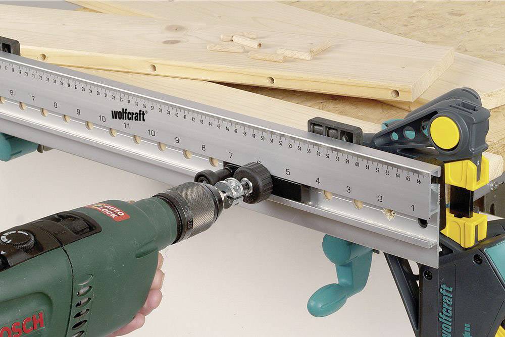 Cordless drill and guide rail positioned on workbench for precise woodworking.
