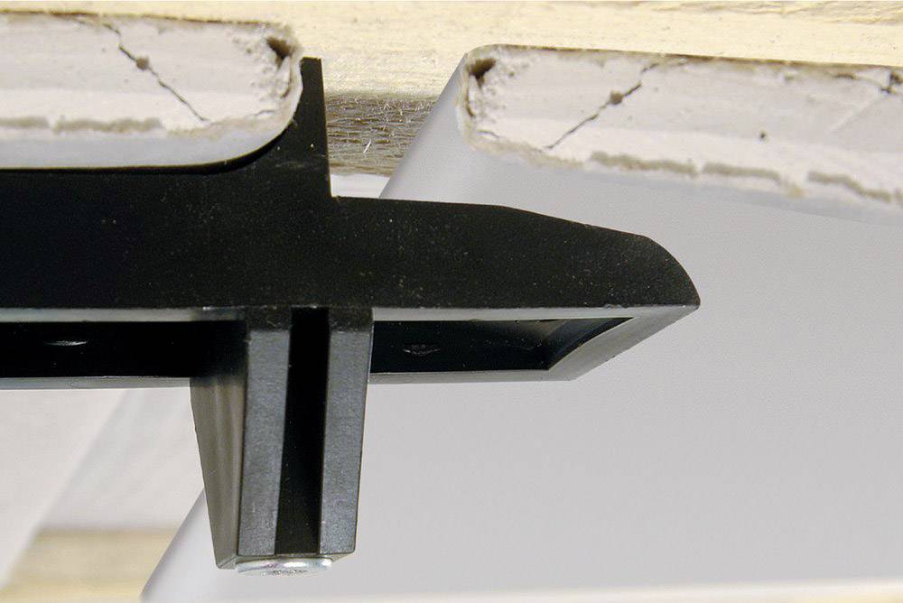 Black cable clip holding a cable beneath a plasterboard ceiling.