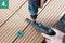 A person is securing a mounting tool to a wooden board using a screwdriver. Step 4 of an assembly process.