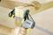 Someone is using a woodworking clamp to join two wooden boards at a right angle. The clamp is grey and yellow.