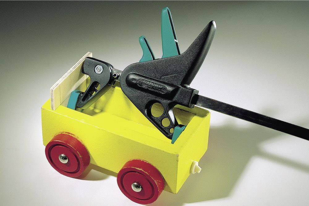 Yellow toy car with red wheels, transporting a black clamp. The car is sitting on a light surface.