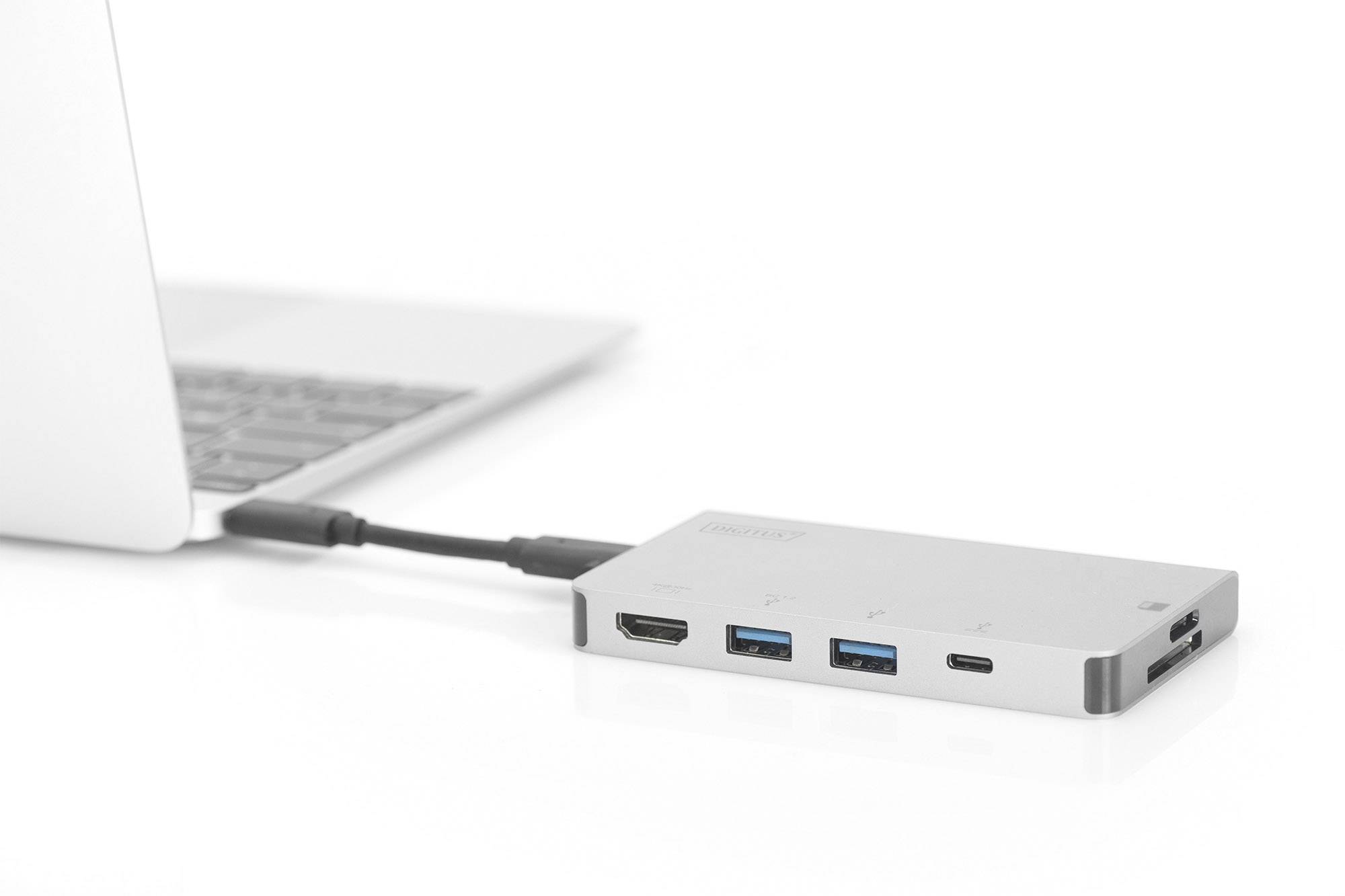 A laptop is connected to a USB-C hub that provides ports for HDMI, two USB-A devices, and USB-C.