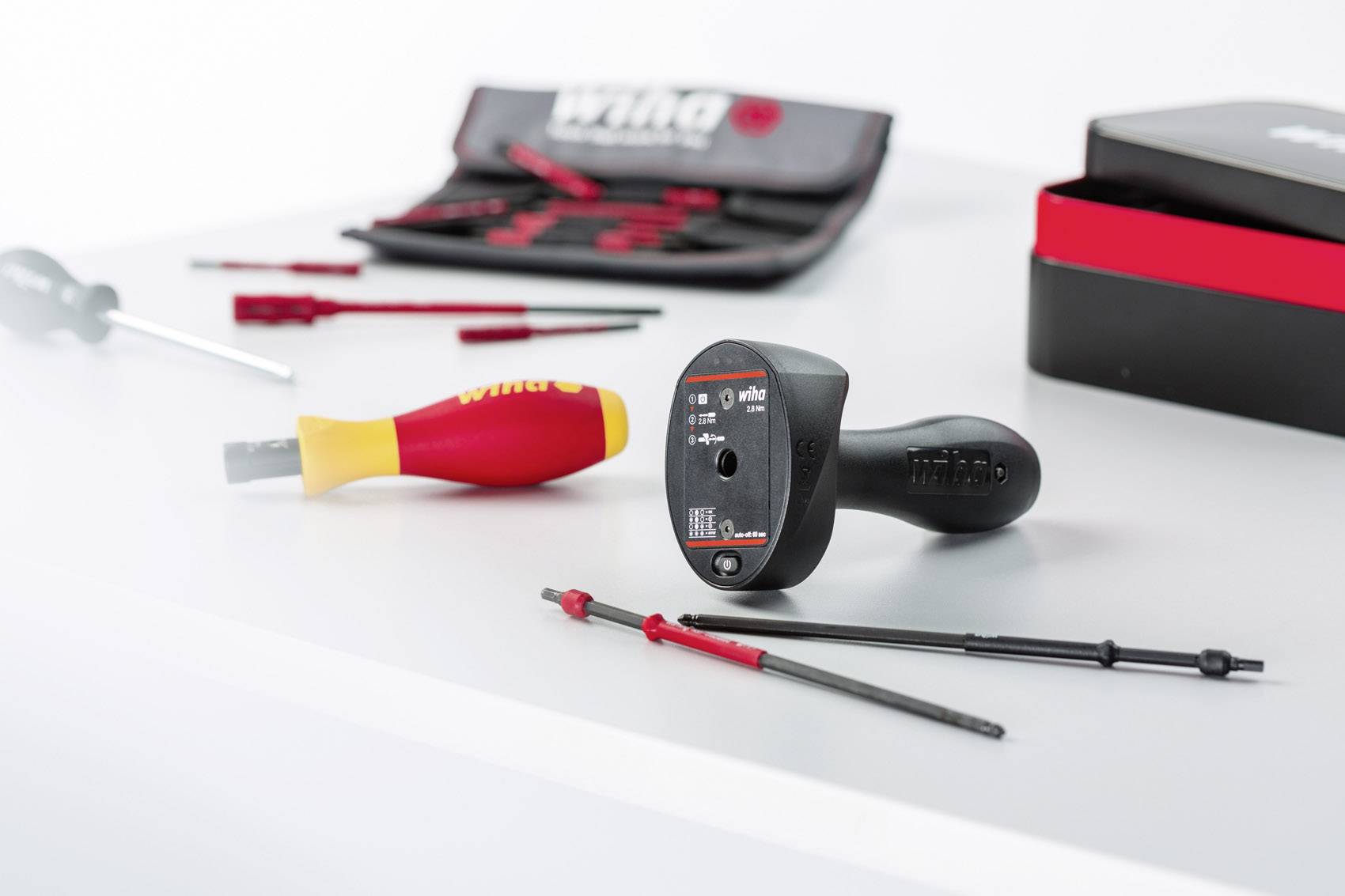 Several screwdrivers and tools are lying on a table. A set of screwdriver bits can be seen in the background.