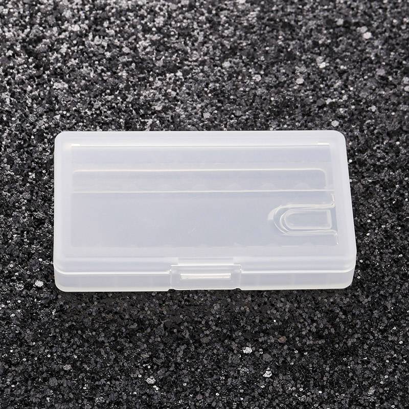 A transparent plastic box is lying on a black, grainy surface.