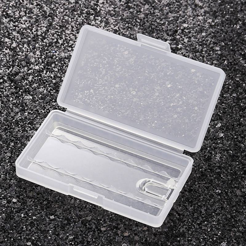 Empty, transparent plastic box with lid open, on a grey, textured background. Sales packaging or storage.