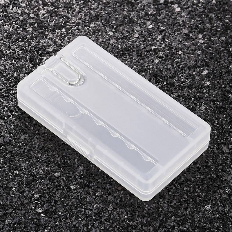 Transparent plastic box on a black granite surface, likely used for storing small items such as paperclips or pins.