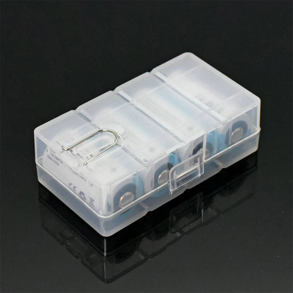 A transparent plastic container holds four inserted batteries, arranged side by side, on a dark surface.