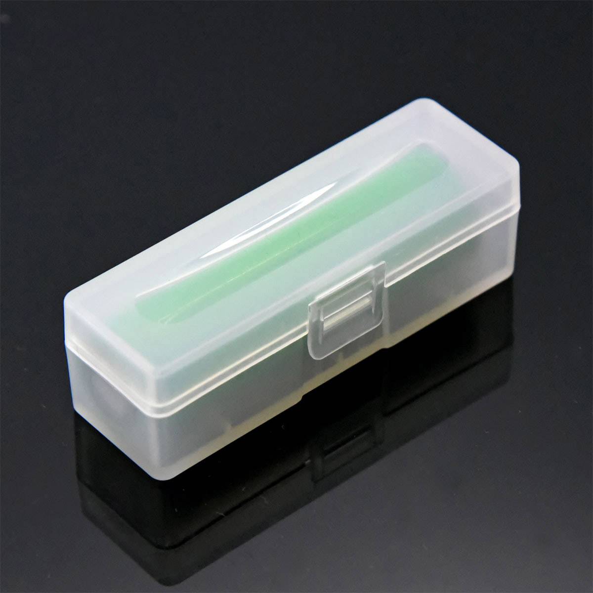 Transparent plastic cassette placed on a black background, containing a green object inside.