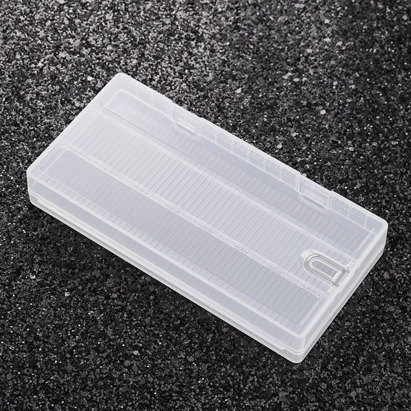 A transparent plastic pencil holder rests on a coarse-grained, black surface.