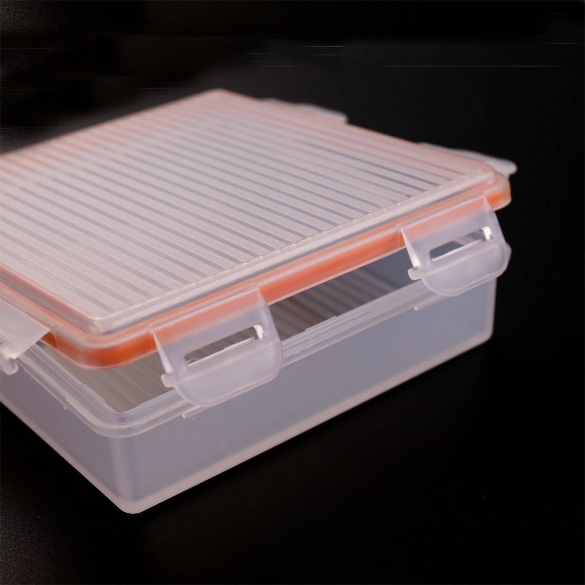 A transparent plastic container with an orange, tightly-sealing lid, suitable for storing food.