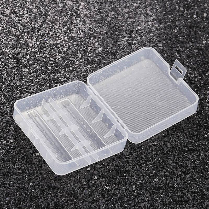 Transparent plastic box, open, with multiple compartments on a black, sparkling background. Box is empty.