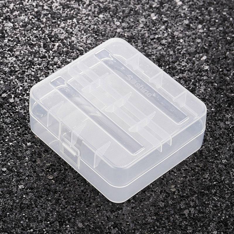 Transparent plastic storage box with compartments on a black, gravel-like surface. Perfect for storing small items.