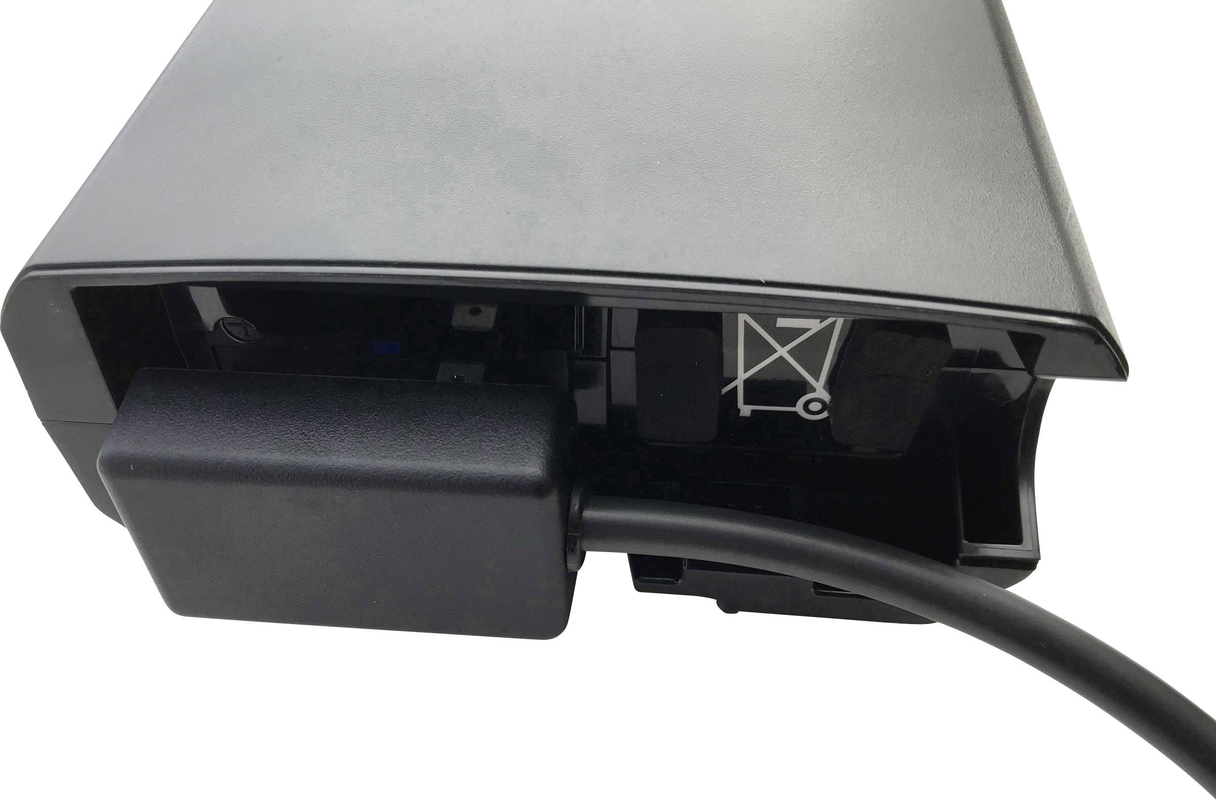 A black electronic device with a cable connected on the side. On the far left, a symbol and a port are visible.