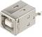 Metallic USB-B socket connector, square-shaped, with four connection points. Suitable for device connections, typical IT application.