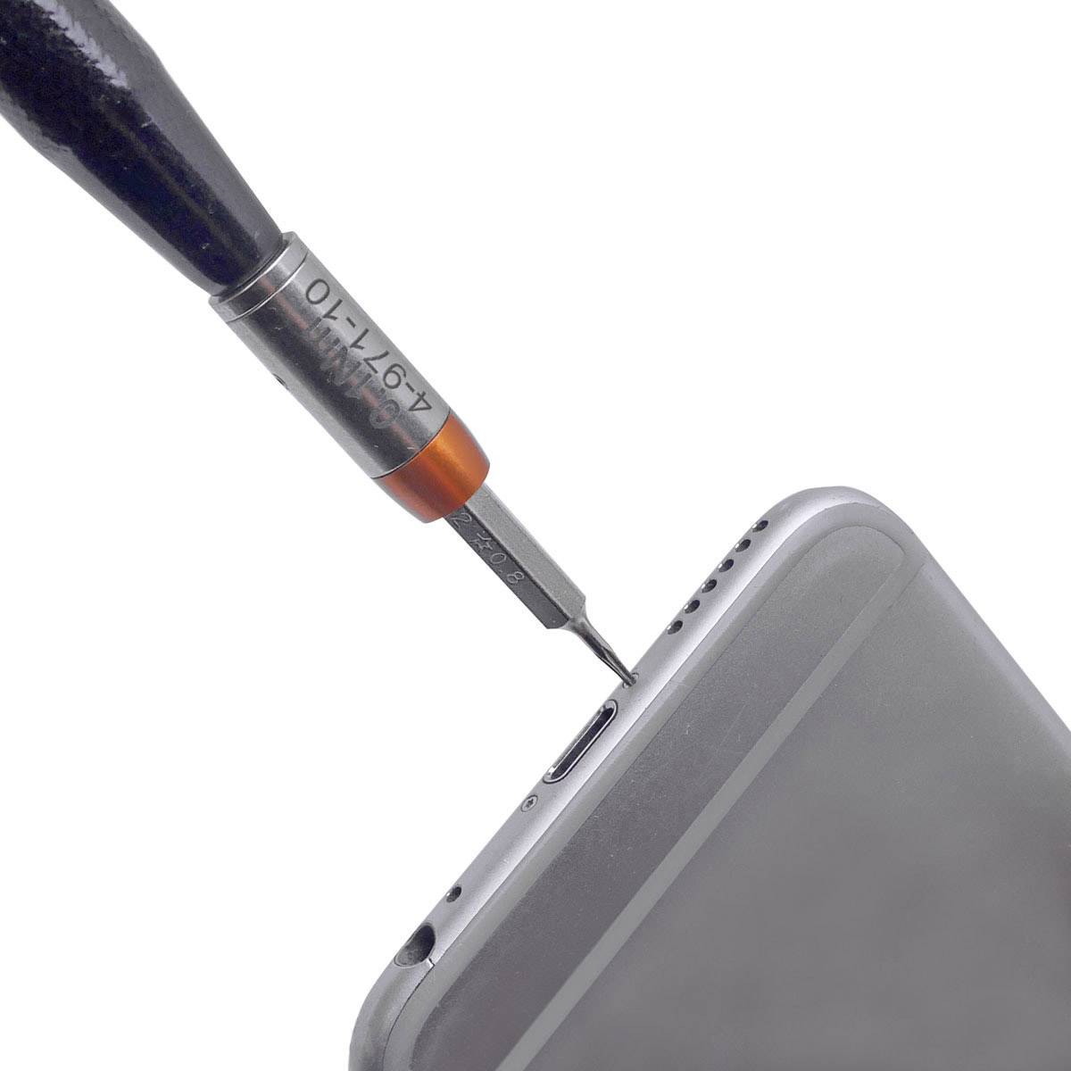 A screwdriver is inserted into the top edge of a smartphone to open or repair it.