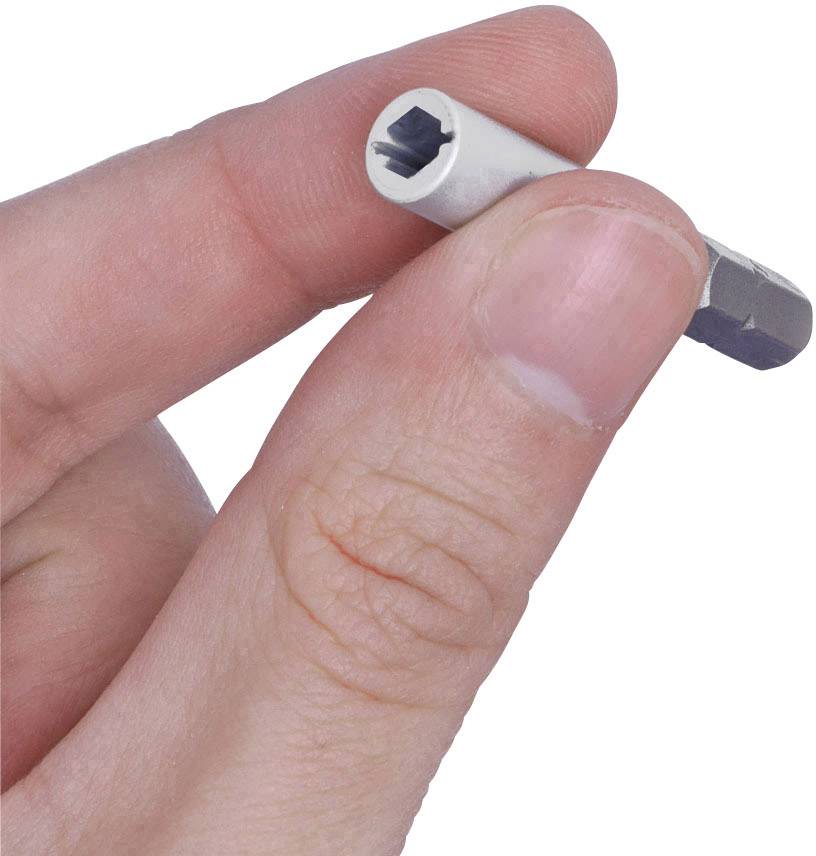 A hand holds a small, silver hexagonal tool between thumb and index finger.