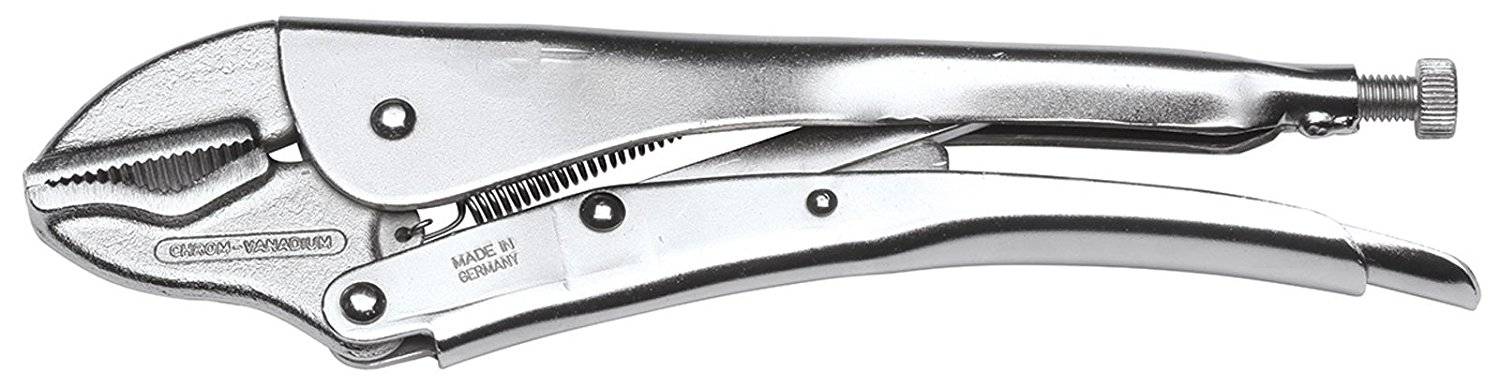 A craftsman is holding pliers against a grinding wheel, generating sparks. A warning notice is affixed to the machine.