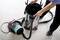 A person opens a vacuum cleaner container to check or replace the filter. The vacuum cleaner is standing on a floor.
